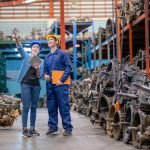 Factory man and woman discuss together with happiness emotion and stand in automotive parts workplace area. Concept of good management and support system for industrial business.